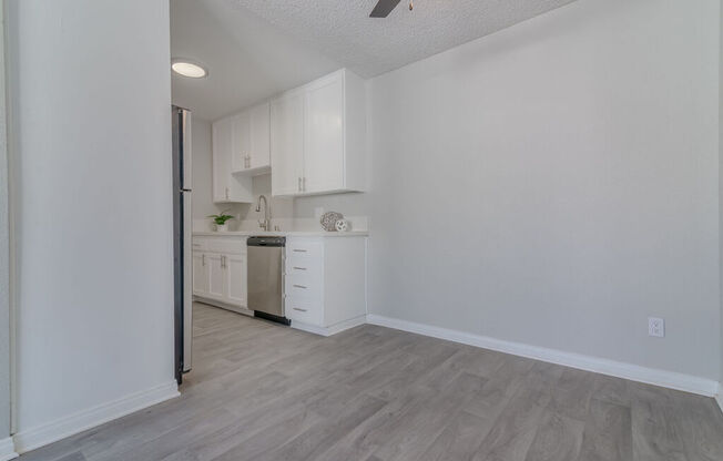 an empty kitchen with white cabinets and white walls and wood floors at Citra Apartments LLC, San Diego, 92107