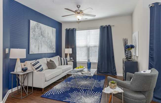 a living room with blue and white furniture and a ceiling fan