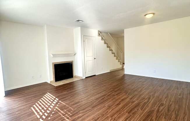 an empty living room with wood flooring and a fireplace