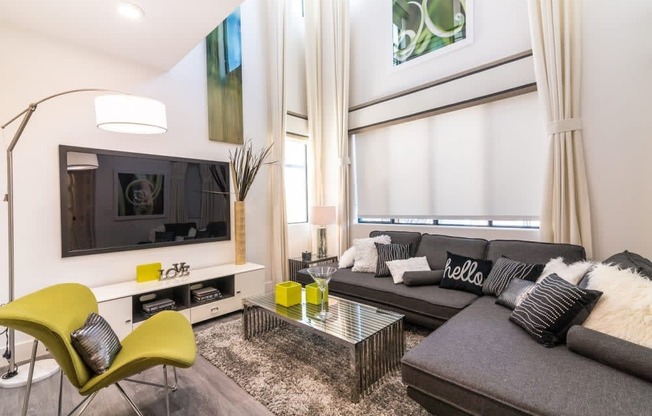 A living room with a tv and blinds and couch and chairs and coffee table