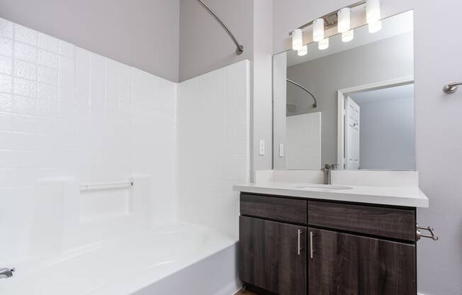 a bathroom with a white tub and a sink and a mirror