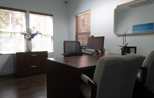 A room with a desk, chairs, and a laptop.,A room with a desk, chairs, and a laptop.