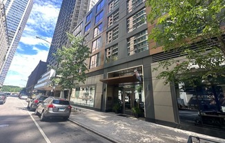 a city street with cars parked in front of a tall building