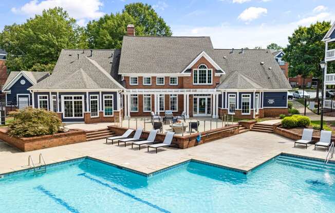a large pool with chairs in front of a large house