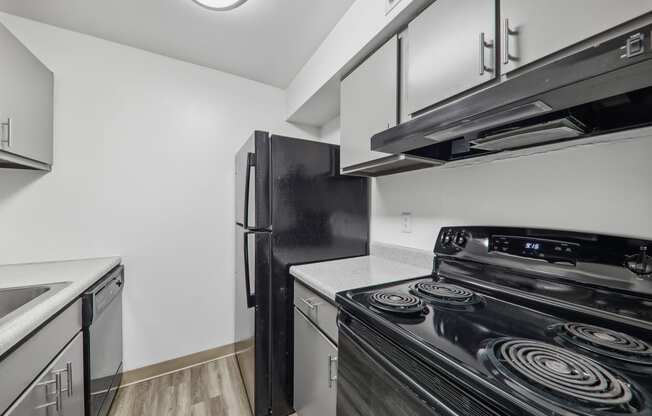 a kitchen with white cabinets and black appliances and a refrigerator