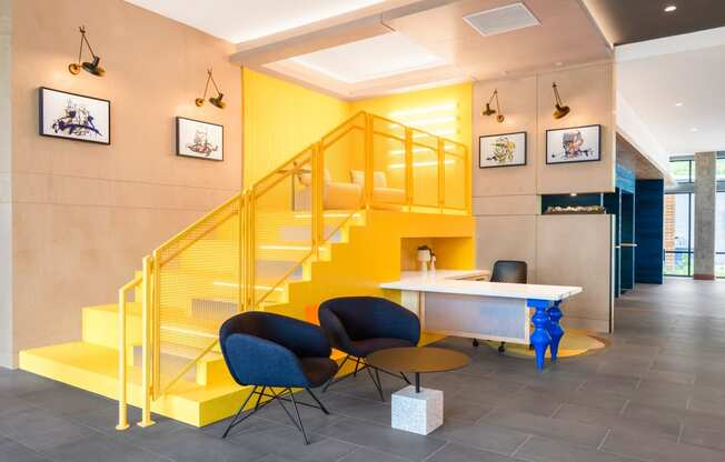 a yellow staircase in a lobby with chairs and a table