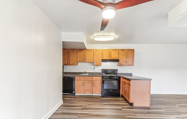 a kitchen with wooden cabinets and black appliances and a ceiling fan