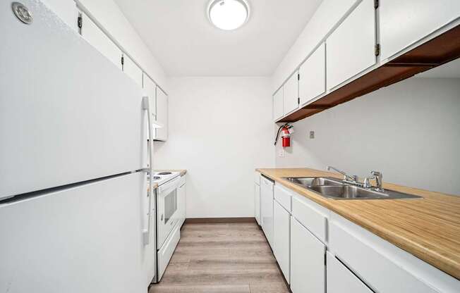 A kitchen with white appliances and wooden countertops.