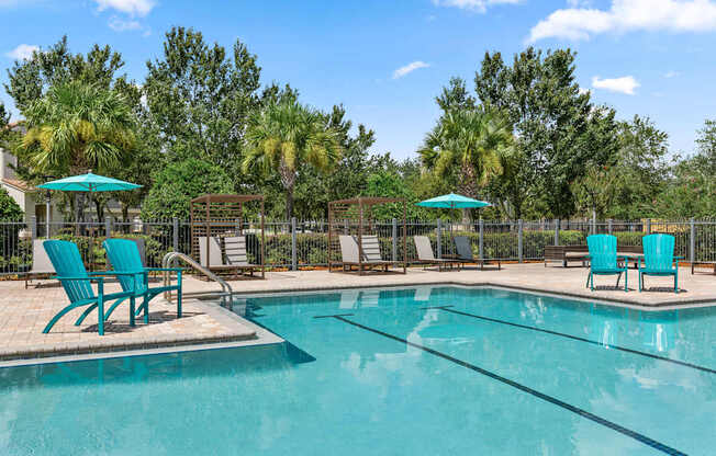 A pool surrounded by trees and chairs.