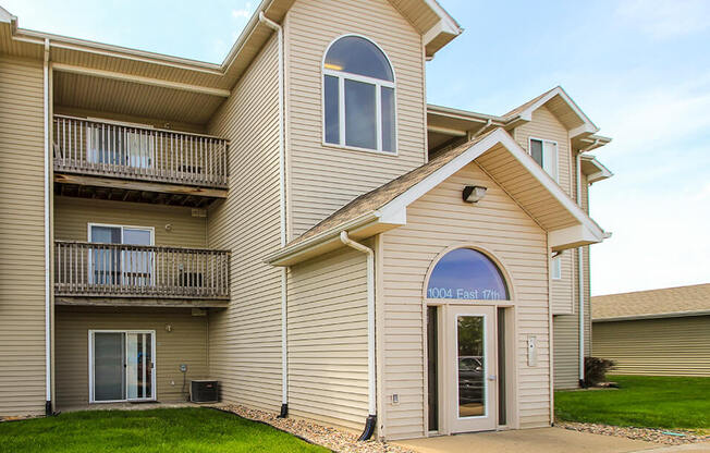 a building with tan siding and a green lawn