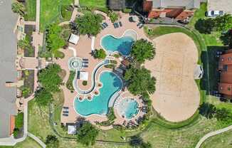 An aerial view of a park with a swimming pool and a sandy area.