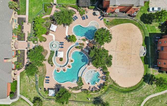 An aerial view of a park with a swimming pool and a sandy area.