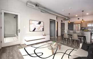a living room with a white rug and a kitchen with a table and chairs
