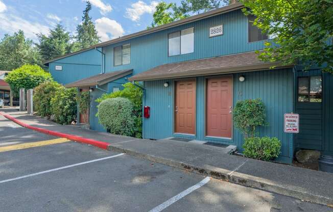 the front of a blue building with a pink door and a sidewalk