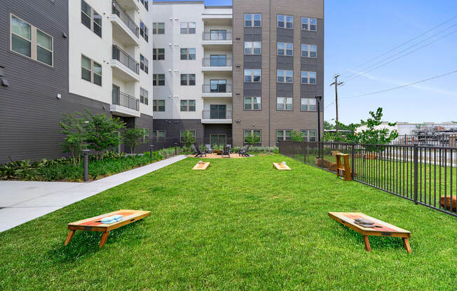 A grassy area with two benches in front of apartment buildings.