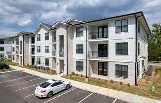 an apartment building with a white car parked in a parking lot