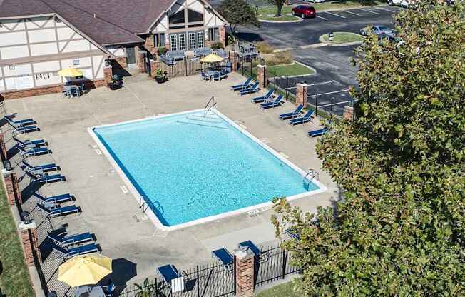 a swimming pool in front of a house with chairs around it