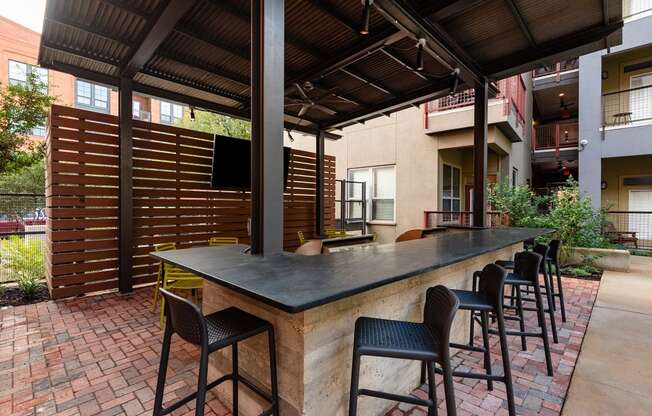 a patio with a bar and chairs in front of a building