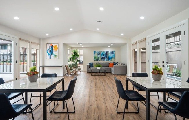 a dining area with tables and chairs and a living room in the background