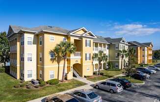 A yellow building with a parking lot in front.