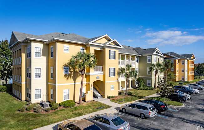 A yellow building with a parking lot in front.