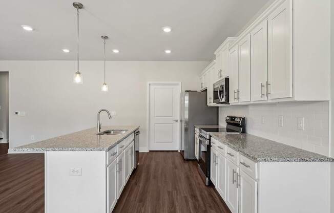 A kitchen with white cabinets and a granite countertop.