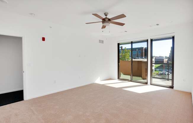 an empty living room with a ceiling fan and glass doors