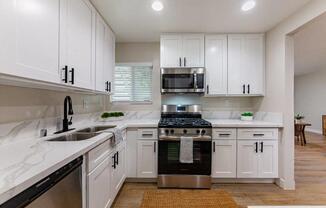 a white kitchen with white cabinets and a black stove