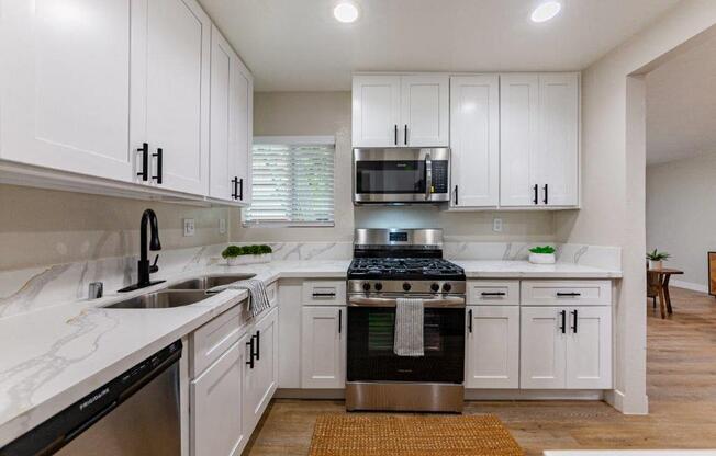 a white kitchen with white cabinets and a black stove