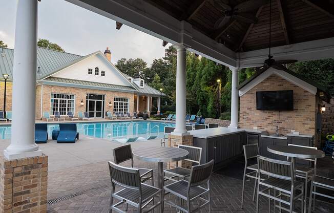 A patio with a table and chairs overlooking a pool.