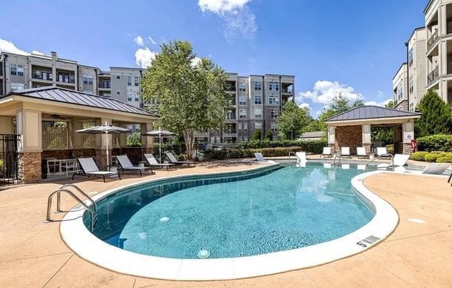 A large outdoor swimming pool surrounded by lounge chairs and umbrellas.