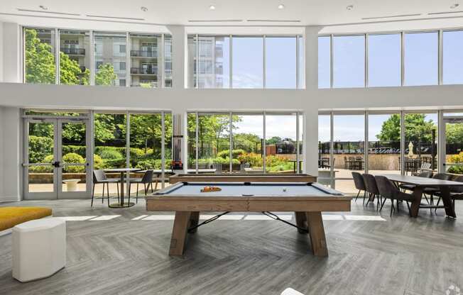 a pool table in a living room with large windows