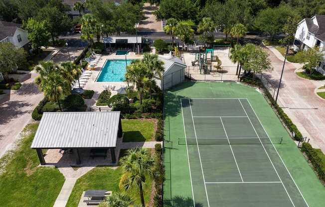 an aerial view of a tennis court and a pool in the backyard of a house