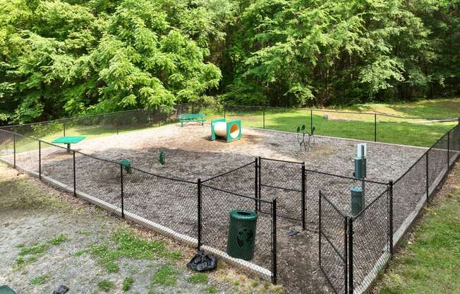 a fenced in area with playground equipment in a park