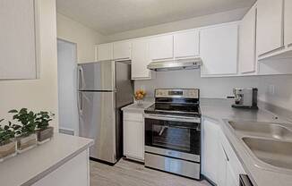 A kitchen with a stainless steel refrigerator, oven, and sink.