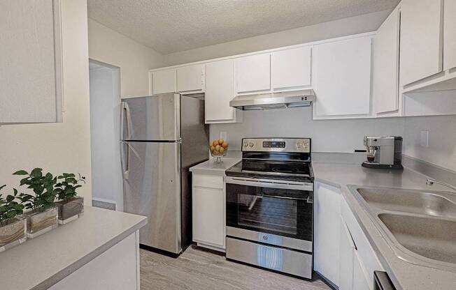 A kitchen with a stainless steel refrigerator, oven, and sink.