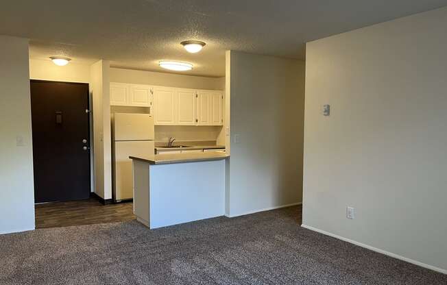 a bedroom with an open door and a kitchen in the background