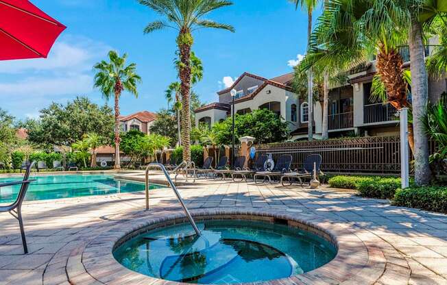 Outdoor spa and pool surrounded by palm trees and lounge seating.