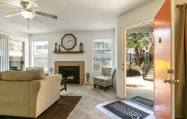 A living room with a beige couch, a fireplace, and a ceiling fan.