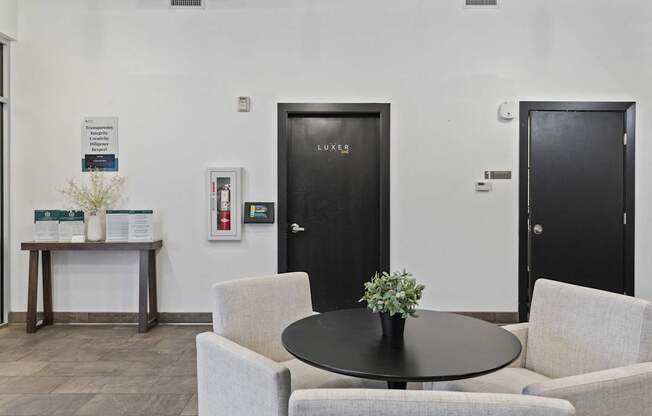 A black door with the word Luxe on it is in a white room.