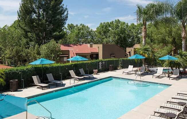 A large swimming pool surrounded by lounge chairs and umbrellas.