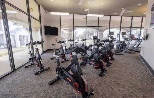 A gym with a row of stationary bikes.