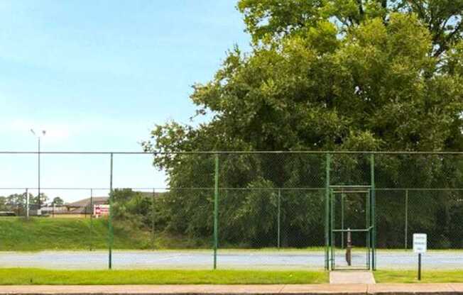 A green fence surrounds a tennis court.