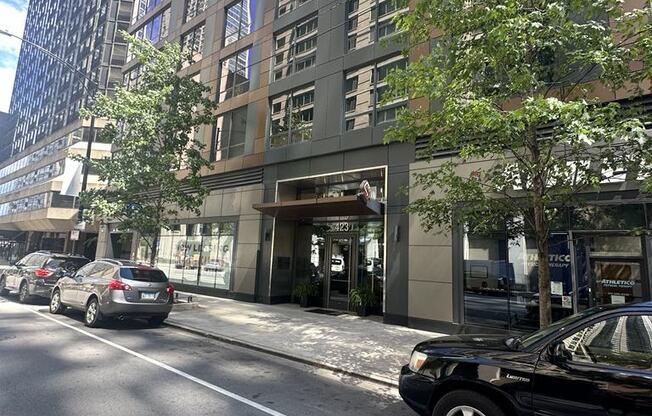a city street with cars parked in front of a tall building