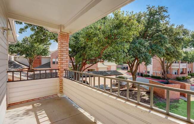 the view from the balcony of a residence with trees and a yard