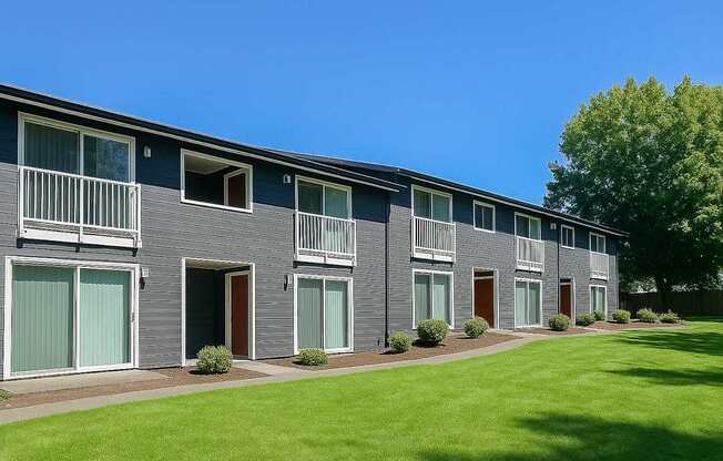 A row of grey houses with green lawns in front.