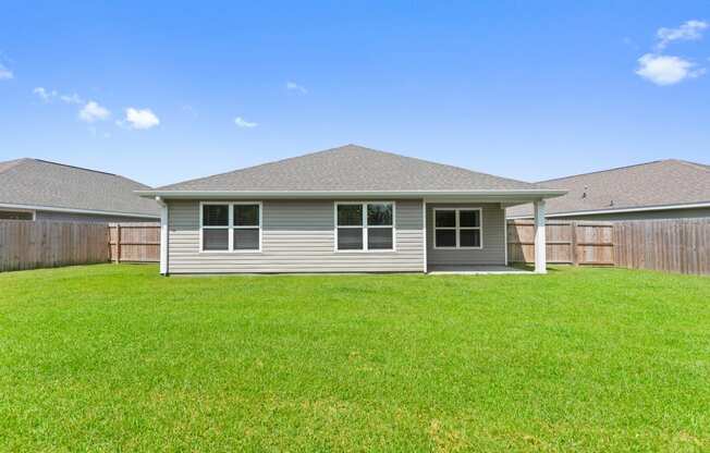 the backyard of a home with green grass and a blue sky