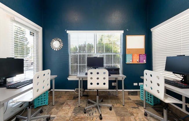 a computer room with desks and chairs and a computer monitor