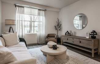 A living room with a white sofa, a round table, and a wooden cabinet.