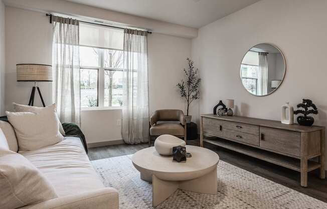 A living room with a white sofa, a round table, and a wooden cabinet.